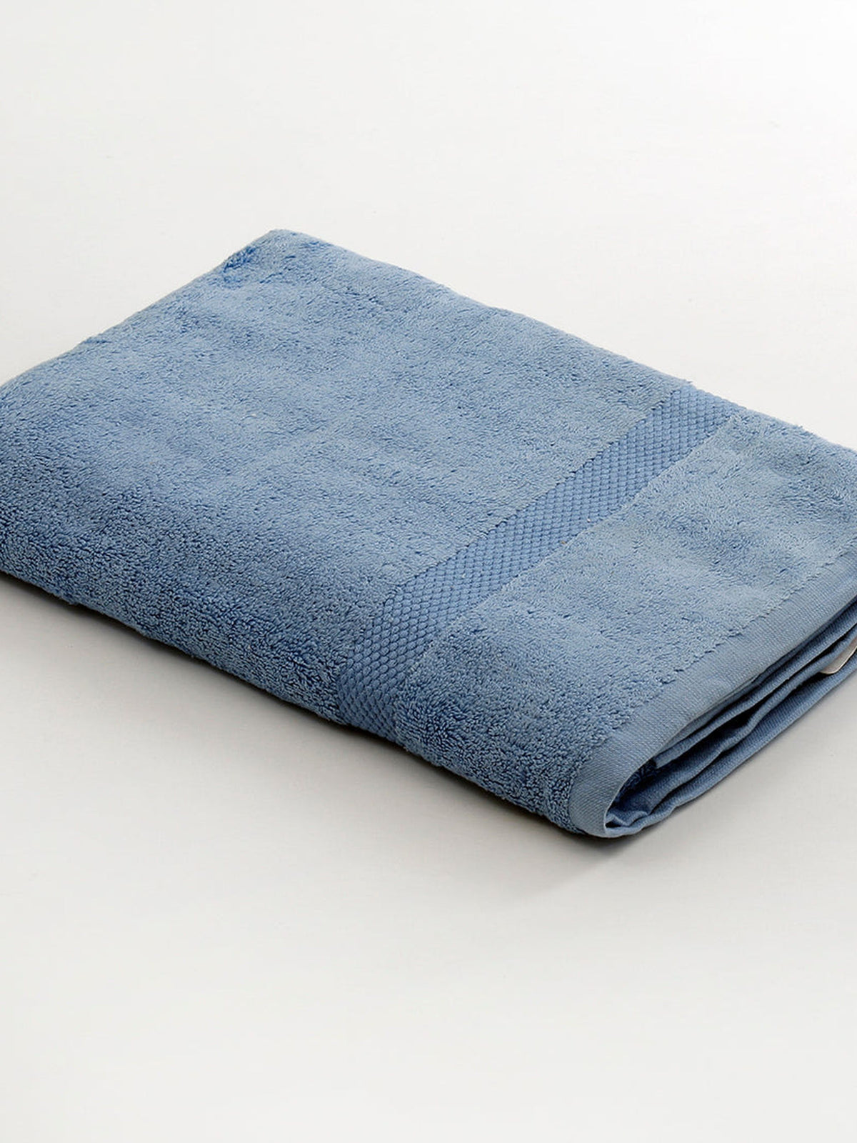 Light blue cotton bath towel folded diagonally with a honeycomb woven border