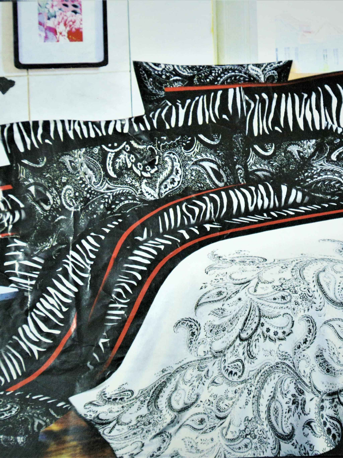 Black and white zebra-stripe and paisley print bedsheet set with a red piping border, styled on a bed with matching pillow covers