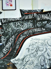 Black and white zebra-stripe and paisley print bedsheet set with a red piping border, styled on a bed with matching pillow covers