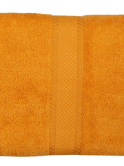 Amber-orange cotton bath towel, close-up folded view showing the diamond-weave border