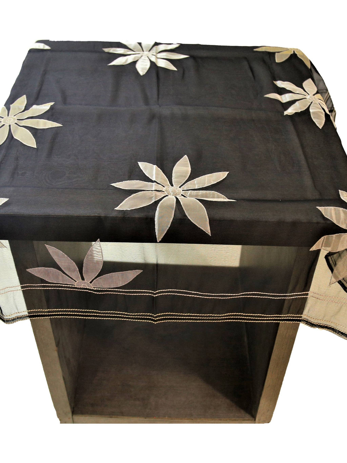 Black sheer organza table cover with a scattered cream appliqué flower pattern and a woven-stripe sheer border, draped over a small display table
