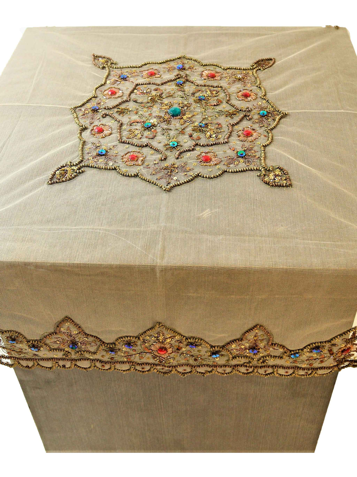 Beige net table cover with a hexagonal gold-beaded floral medallion embroidered at the centre, accented with red and turquoise stones, and a matching beaded scalloped border