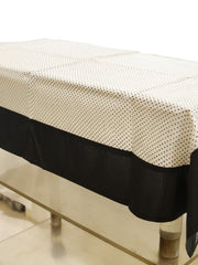 White sheer table cover with a scattered black polka-dot print, set over a solid black underskirt