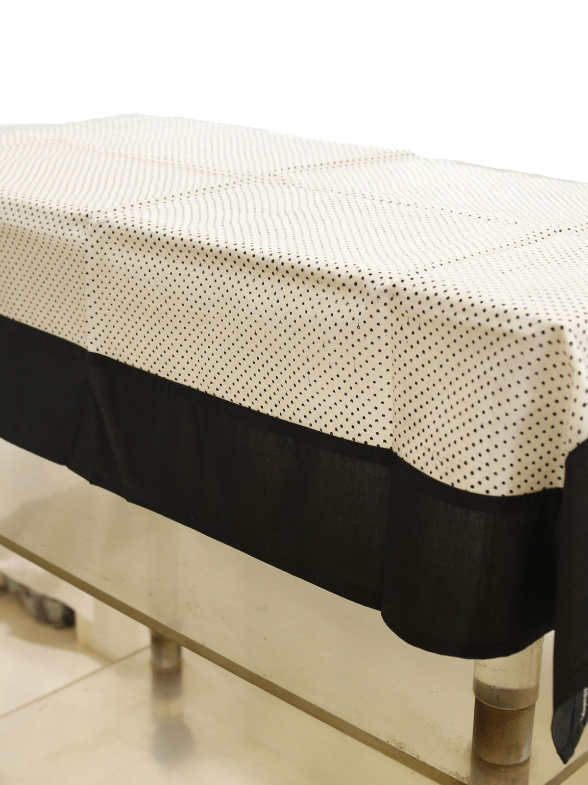 White sheer table cover with a scattered black polka-dot print, set over a solid black underskirt