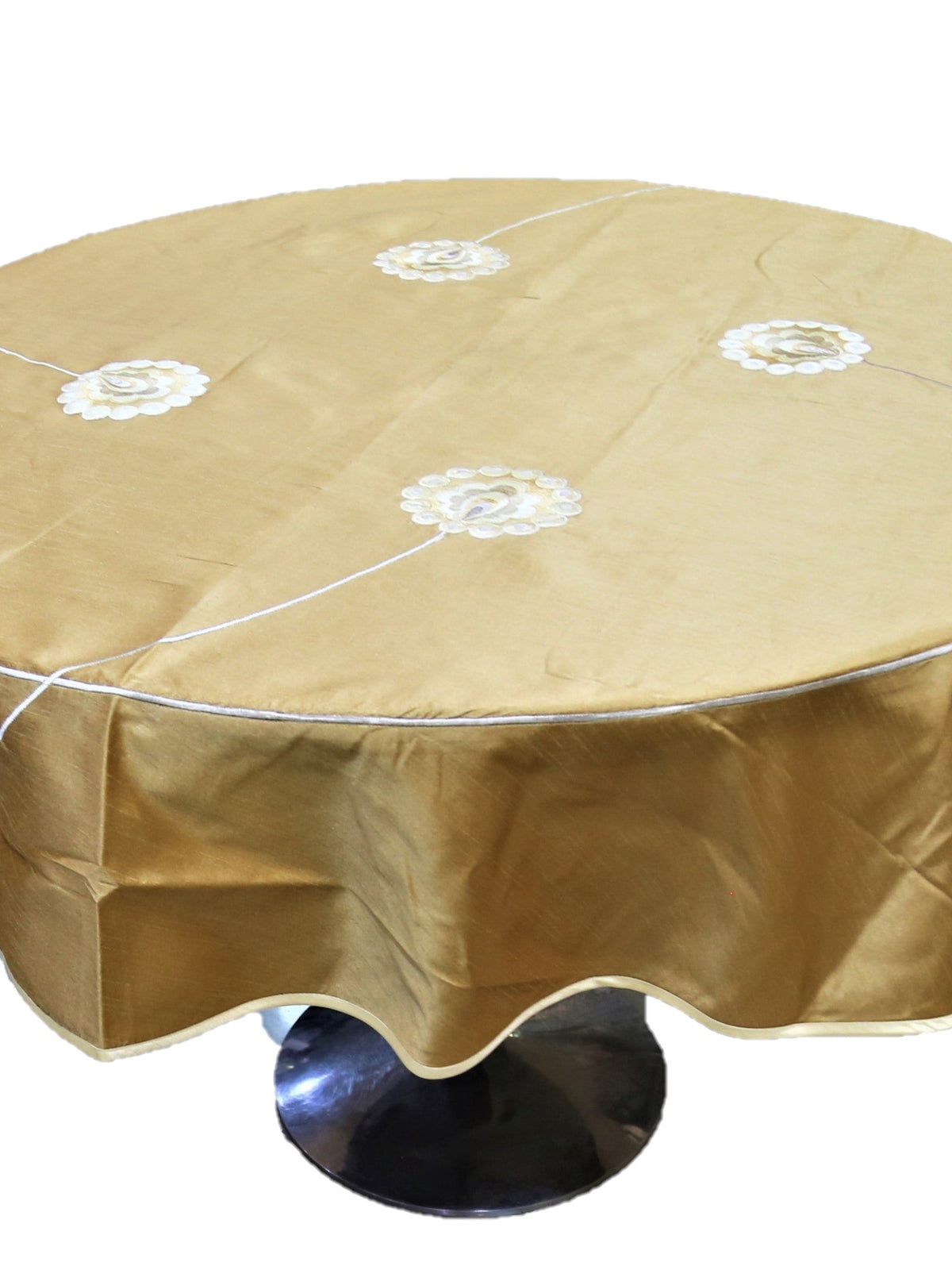Round solid gold table cover with scattered white flower appliqués and a scalloped hem