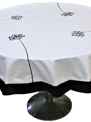 Round cream table cover with scattered black-outlined floral appliqué medallions and a black underskirt