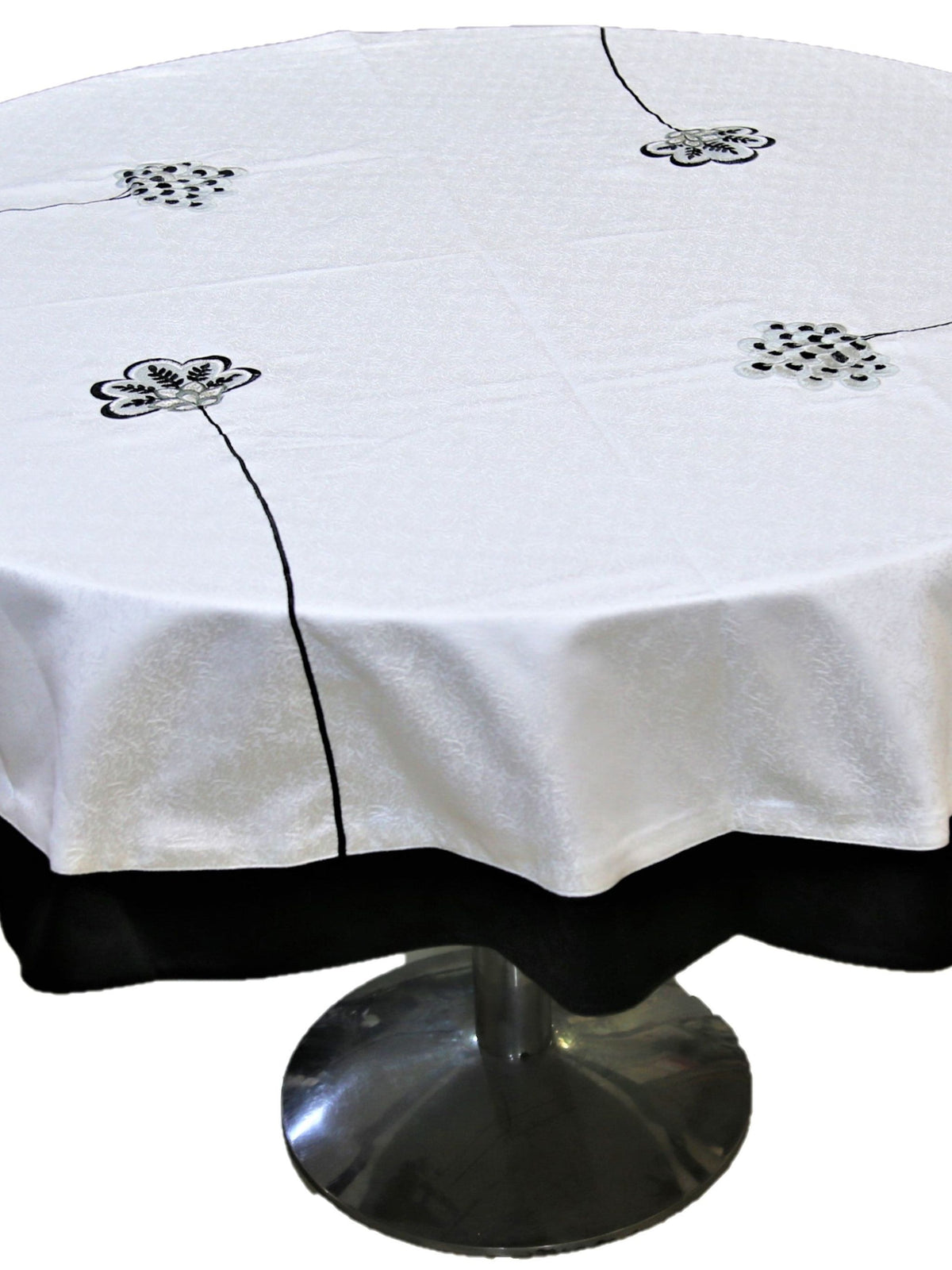 Round cream table cover with scattered black-outlined floral appliqué medallions and a black underskirt