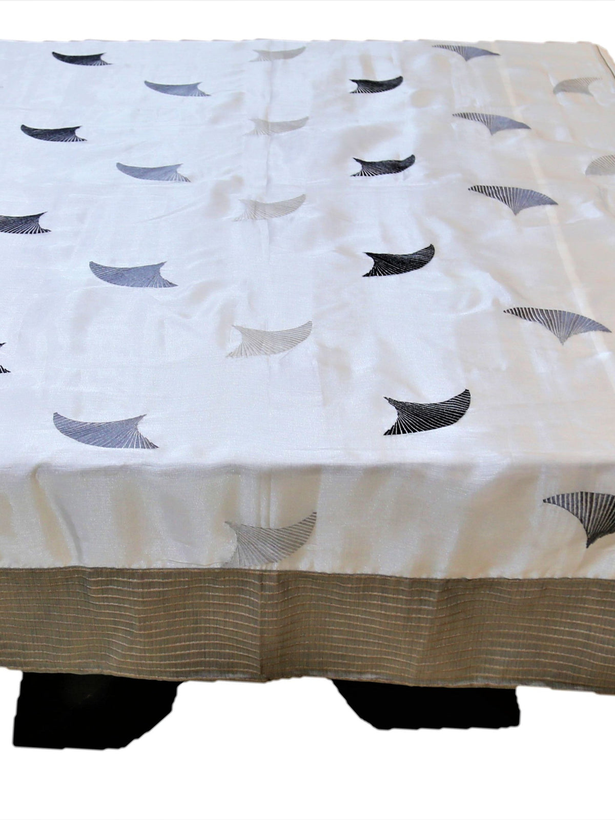White table cover with grey embroidered fan-shaped motifs and a beige striped border