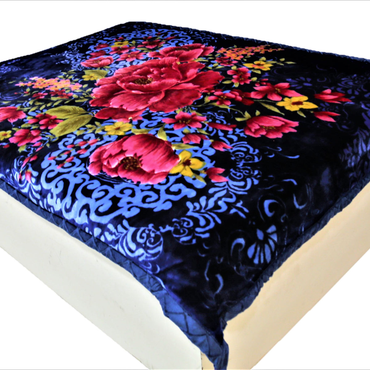Navy-blue velour blanket with a large red-pink peony floral print and pale-blue scroll damask pattern, spread over a bed
