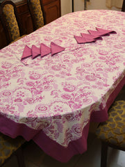 Off-white oval table cover set with a pink and purple paisley floral print, a solid mauve-pink border, and matching mauve triangle-folded napkins