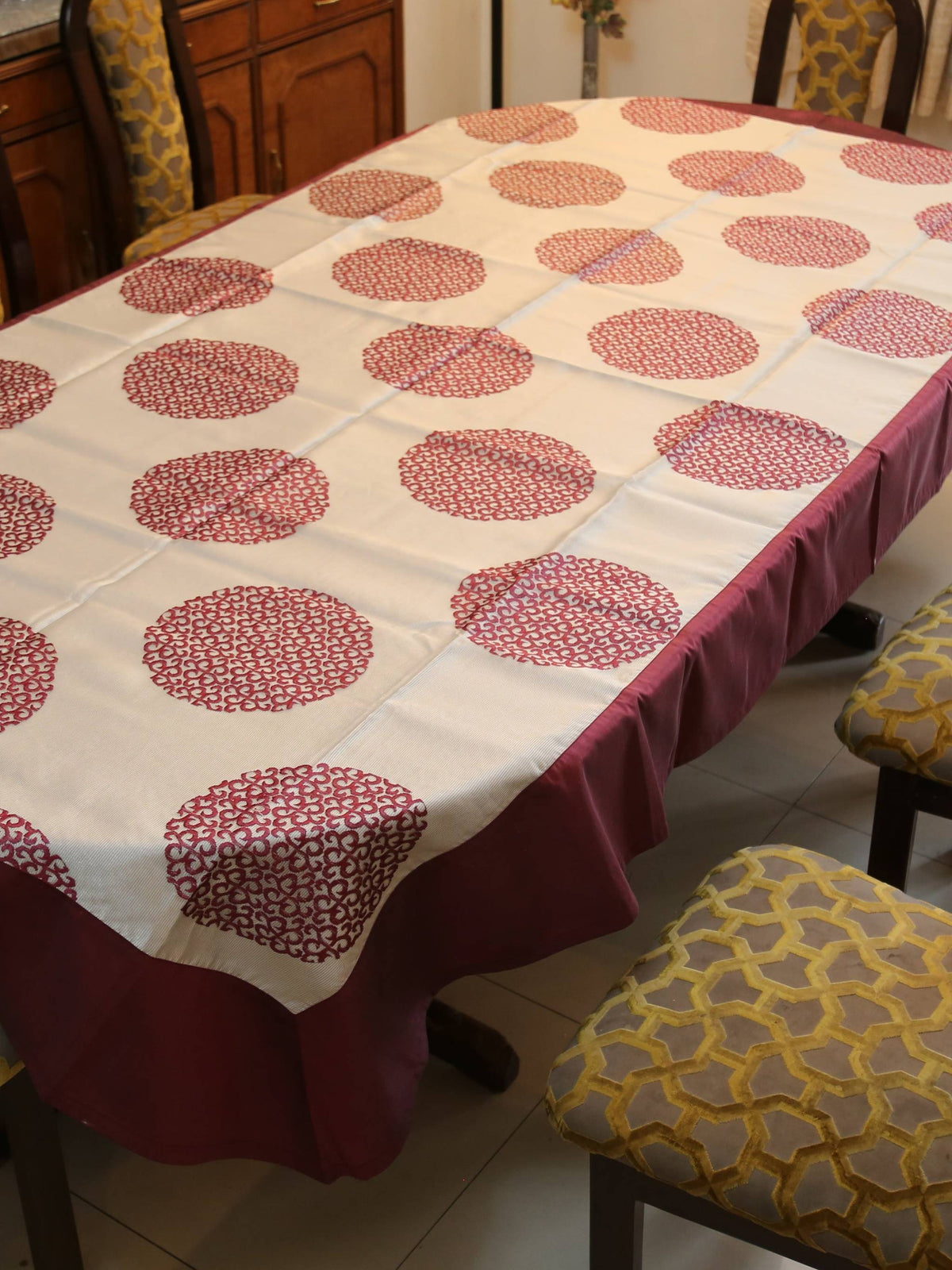 White oval table cover with a maroon circular medallion print and a solid maroon border