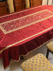 Maroon silk table cover with a gold-bordered floral embroidered runner panel down the centre