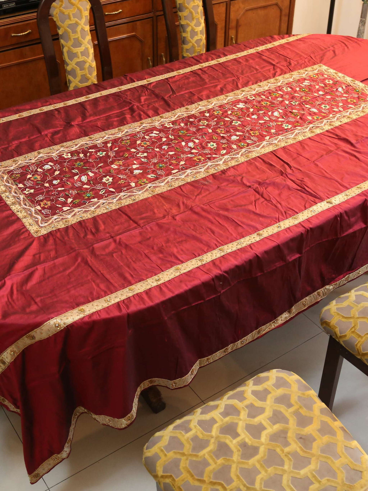 Maroon silk table cover with a gold-bordered floral embroidered runner panel down the centre