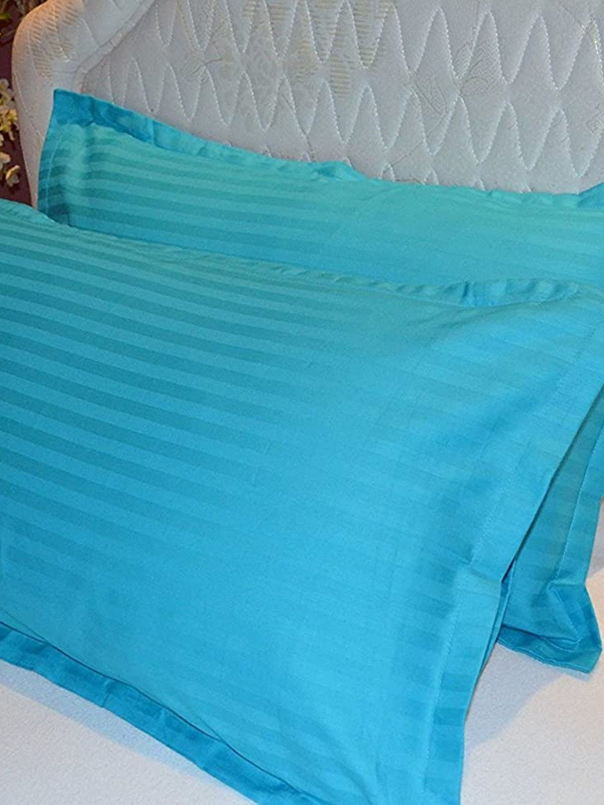 Turquoise cotton satin pillow covers with a self stripe, shown on a bed, 18x27 inch