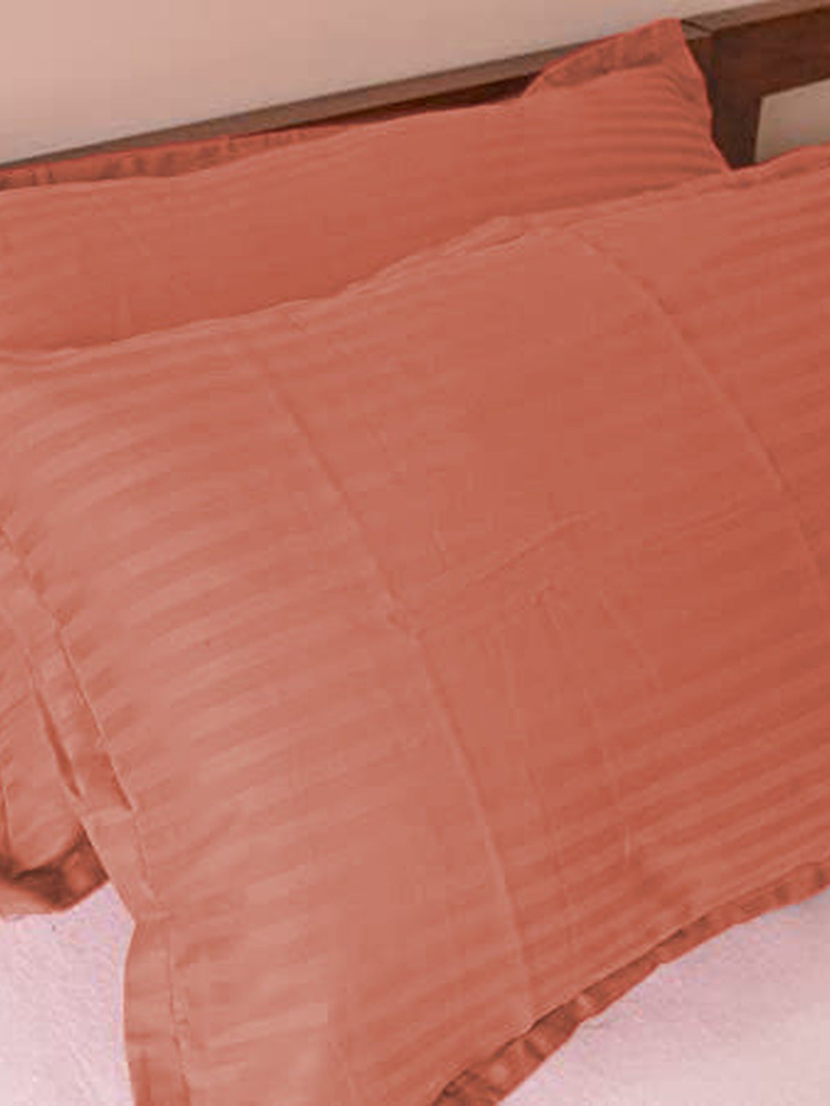 Terracotta cotton satin pillow covers with a self stripe, shown on a bed, 18x27 inch
