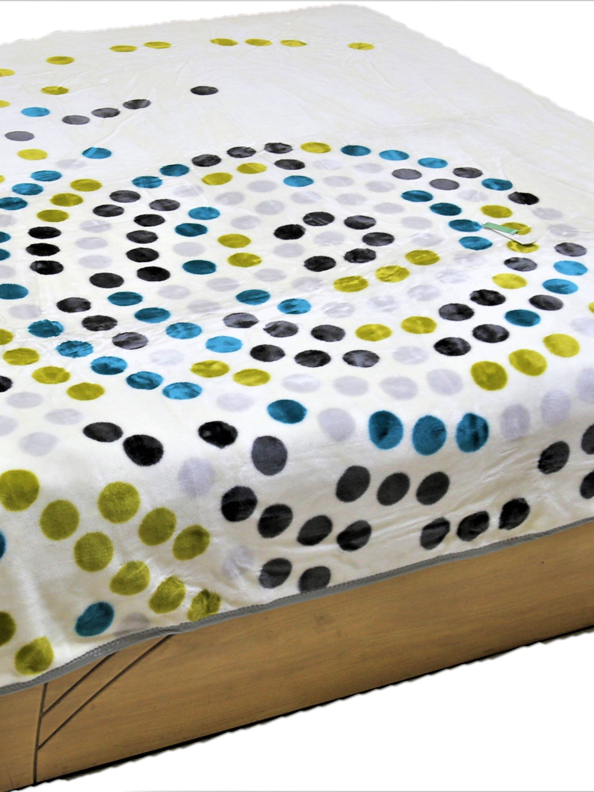 White-cream blanket with a swirled spiral polka-dot pattern in black, teal-blue, olive-green, and light-grey circles