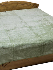 Pale sage green fur-finish blanket spread over a double bed, Monaco