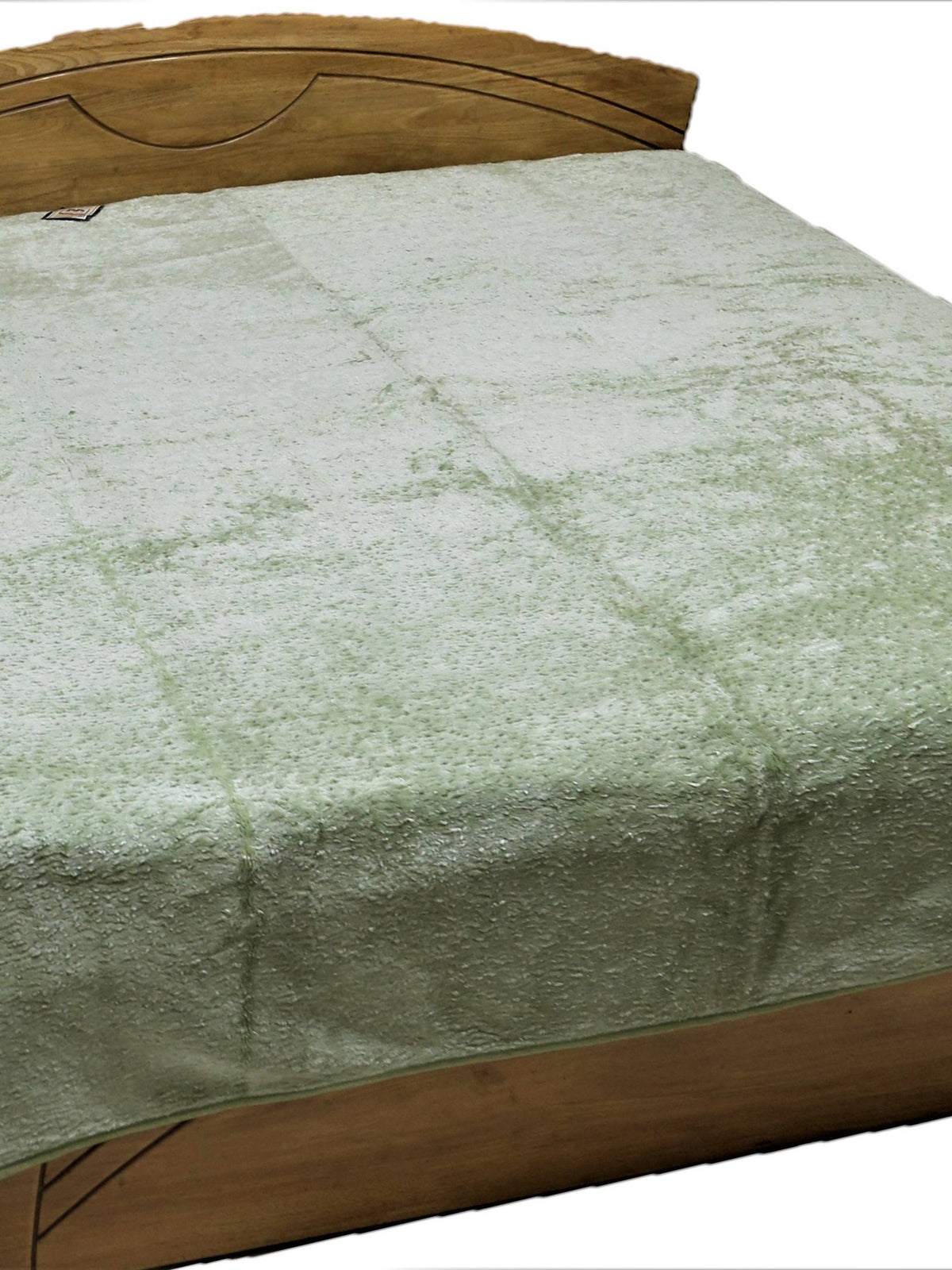 Pale sage green fur-finish blanket spread over a double bed, Monaco
