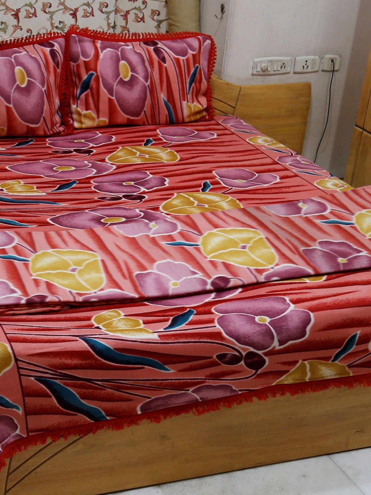 Coral-red blanket set with a mauve-purple and mustard-yellow poppy floral print, styled with matching pillow covers