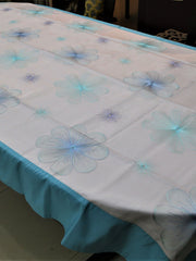White oval table cover with a blue and purple embroidered flower pattern and a solid teal-blue border