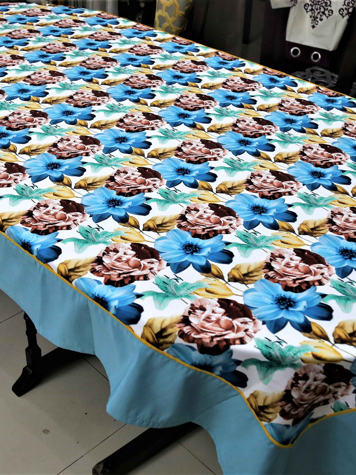 White table cover with a large blue, brown, and teal floral print and a solid light-blue underskirt with gold piping
