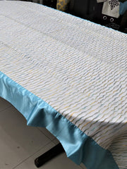 Cream table cover with a wavy multicolour stitch-line pattern and a solid sky-blue satin border