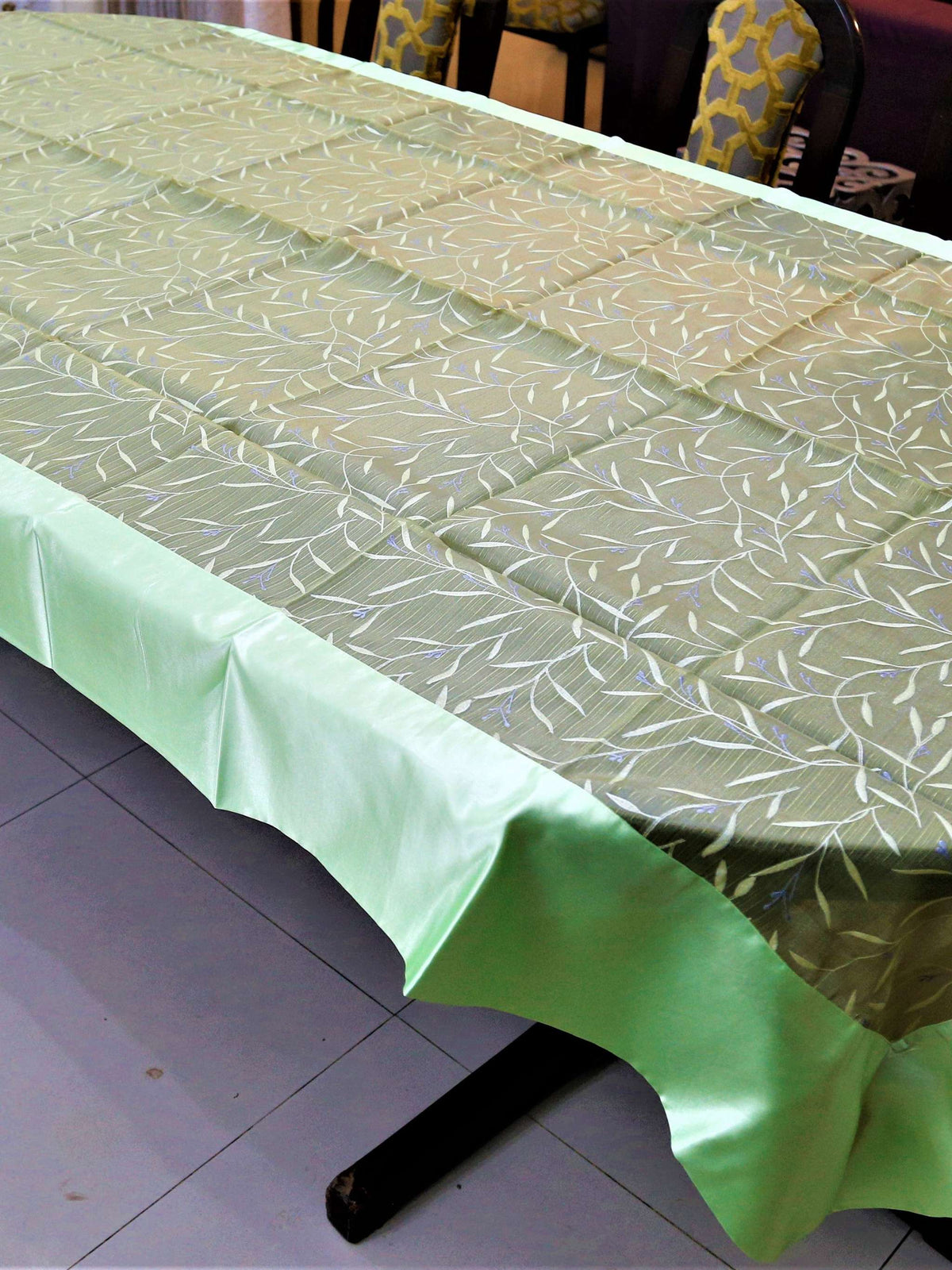 Olive-green table cover with a white and silver embroidered leaf-and-vine pattern and a pale mint-green satin border