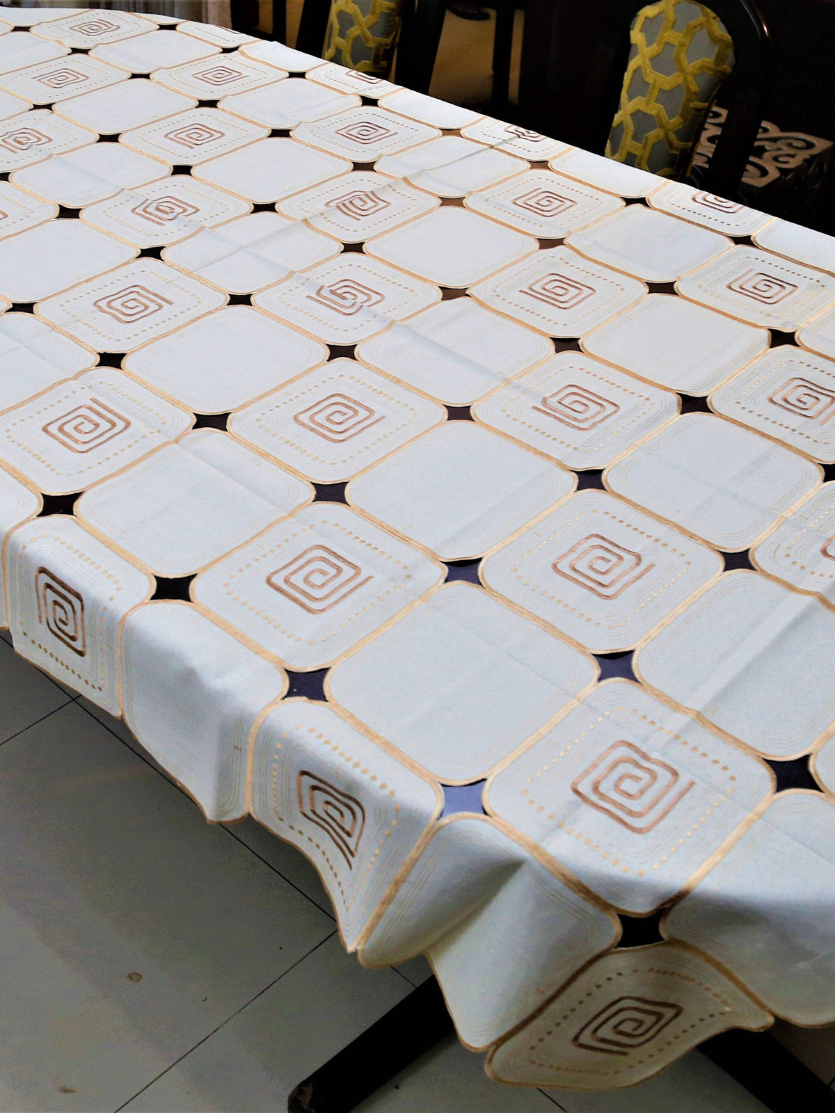 White-ivory table cover with a geometric cutwork square pattern and brown scroll motifs inside each square