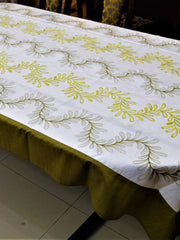 White table cover with a green and yellow embroidered fern-leaf vine pattern and a solid olive-green underskirt