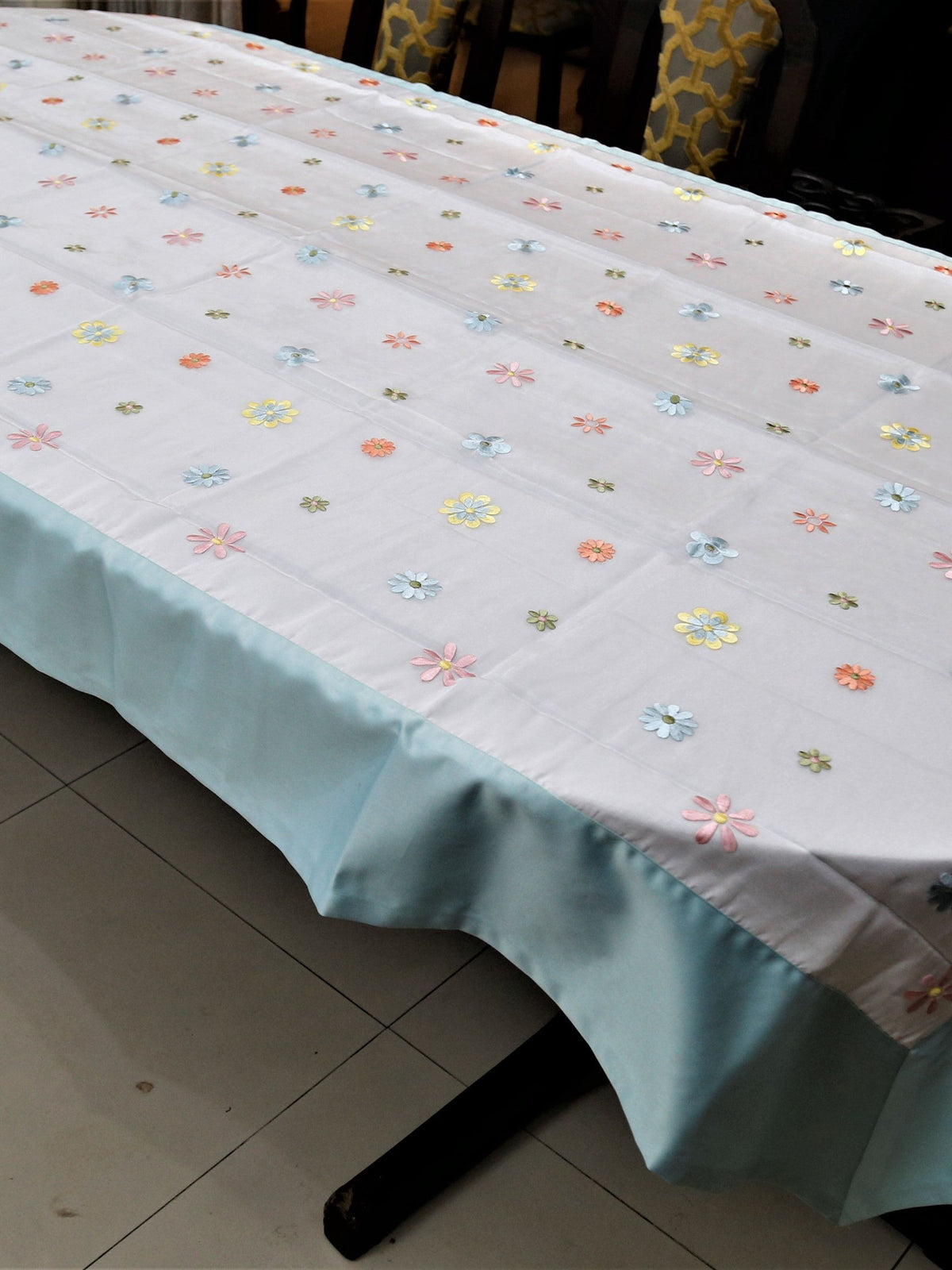 White table cover with a sequinned multicolour daisy dot pattern and a solid sea-green satin border