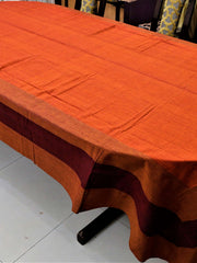 Solid rust-orange table cover with a maroon and rust horizontal striped border