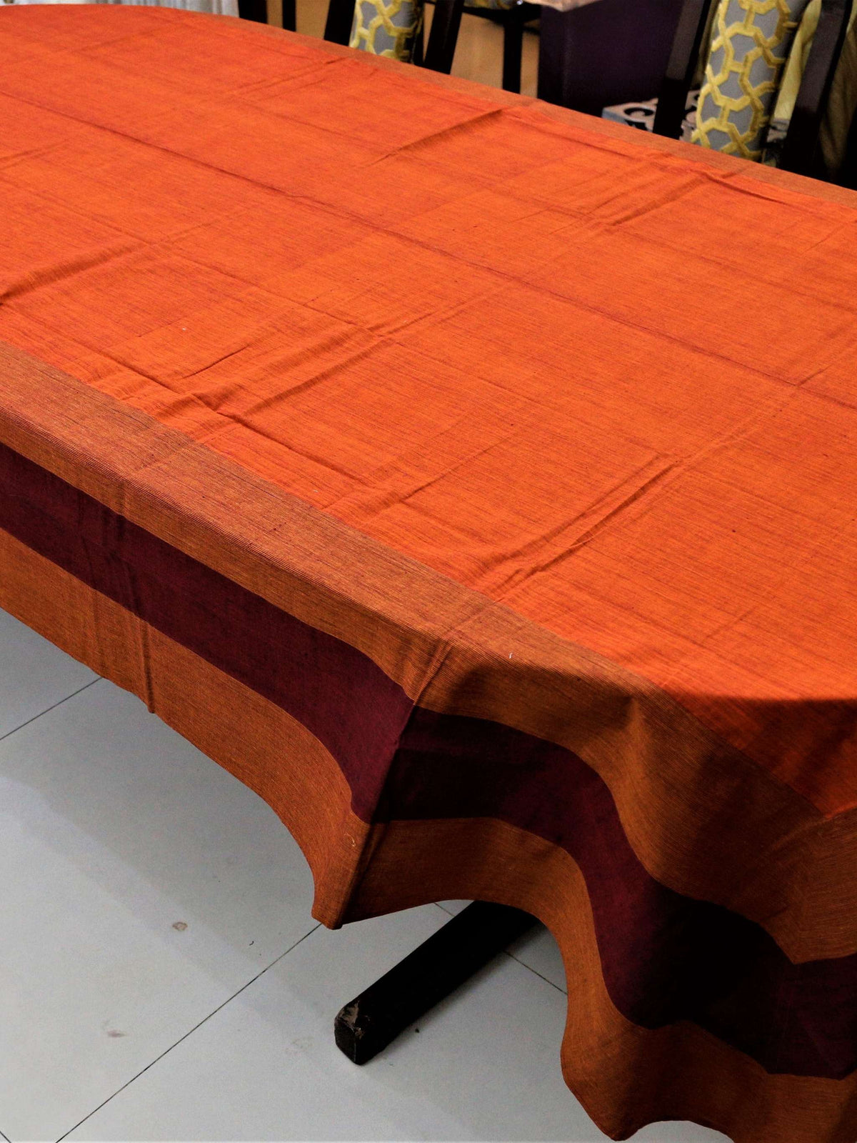 Solid rust-orange table cover with a maroon and rust horizontal striped border