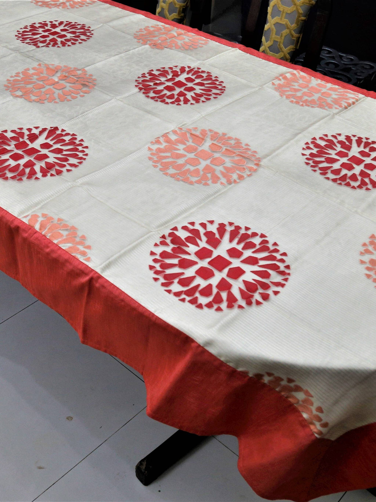 Cream table cover with a cutwork circular floral medallion pattern and a solid gajri-red border
