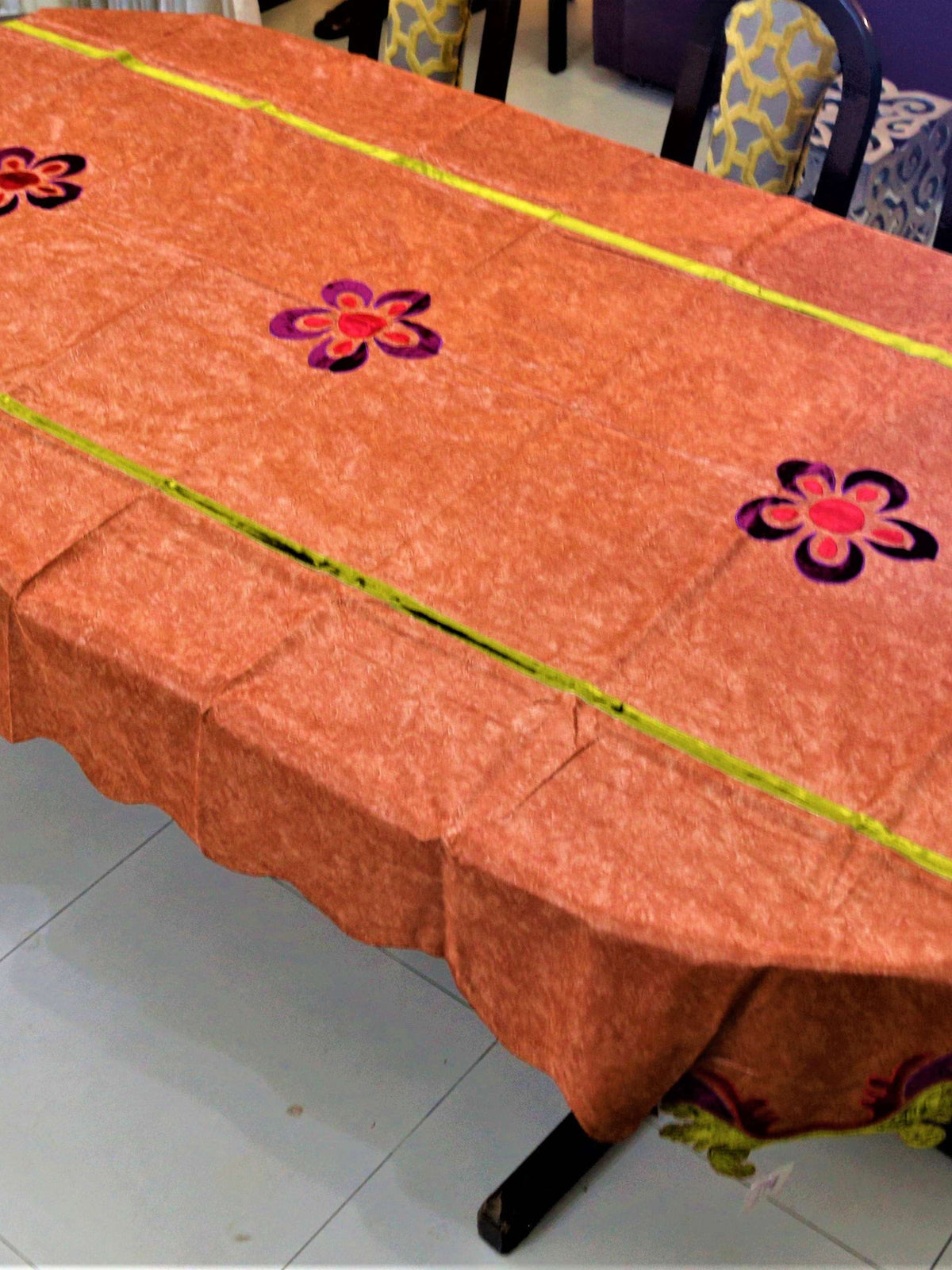 Rust-orange velvet-look table cover with purple and pink flower appliqué motifs and a lime-green piped seam