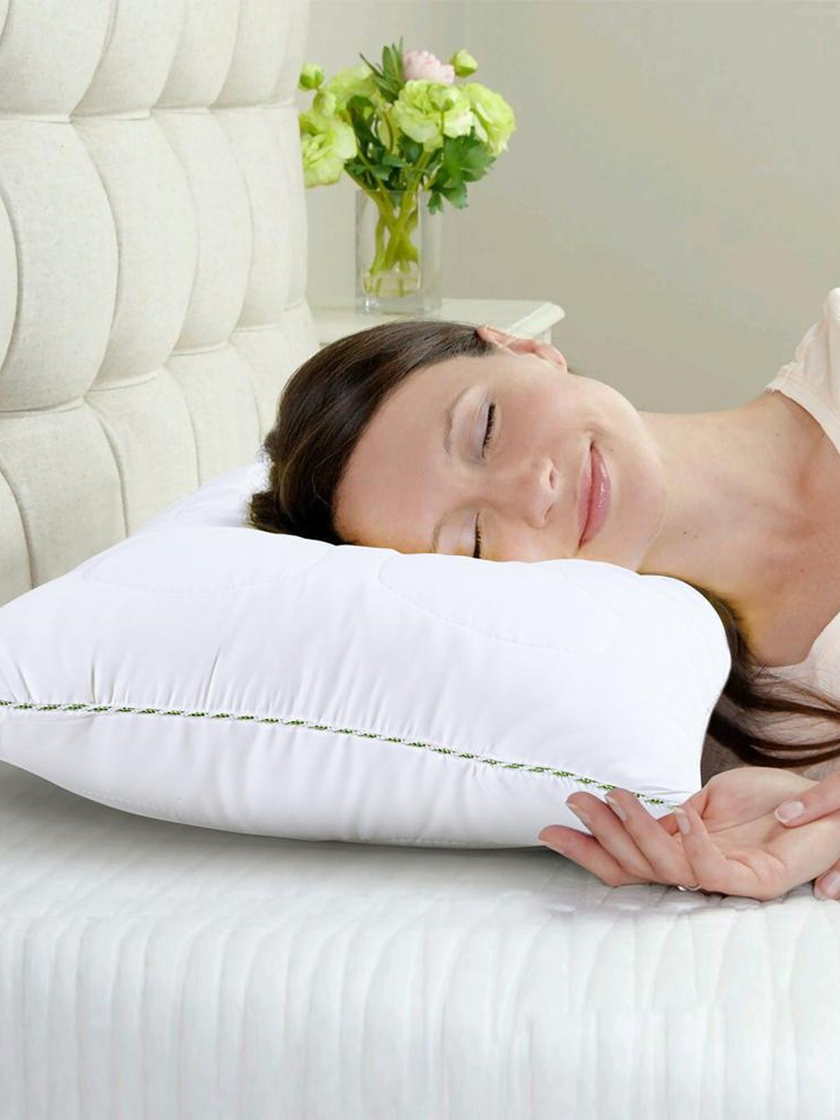Woman asleep on the white Tencel pillow with its green corded edge, on a made bed