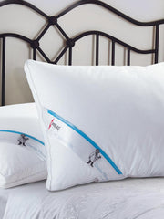 Two white Doctor Pillows with blue Spread branding on a metal framed bed