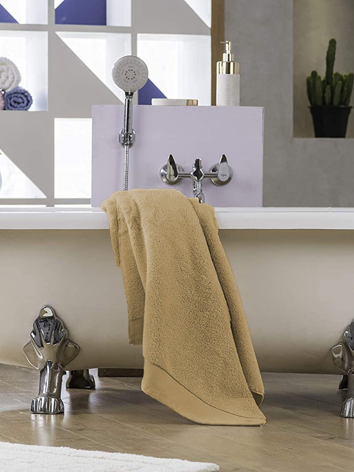 Beige Micro Cotton Lea Blanc bath towel draped over a freestanding bathtub in a modern bathroom