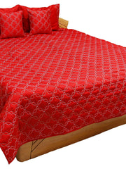 Red quilted double bedcover with a white diamond-lattice embroidery, styled with matching pillow and cushion covers on a wooden bed frame