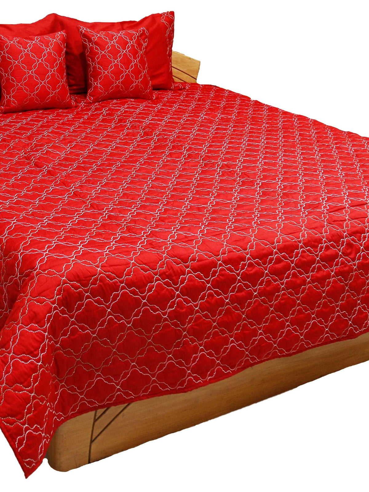 Red quilted double bedcover with a white diamond-lattice embroidery, styled with matching pillow and cushion covers on a wooden bed frame