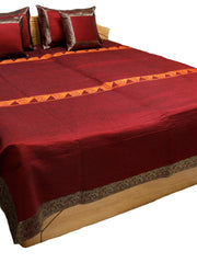 Maroon-red satin double bedcover with a grey-brown zari-brocade border, styled with matching pillow and cushion covers