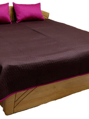 Aubergine quilted bedcover with magenta pillow covers and pink piped edge, angled view