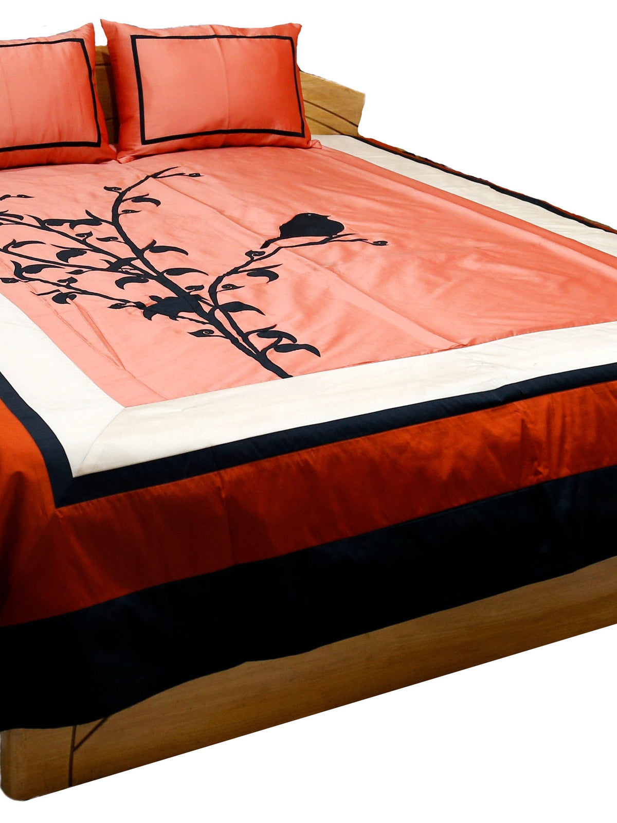 Coral applique bedcover with black bird on branch and coral pillow covers, angled