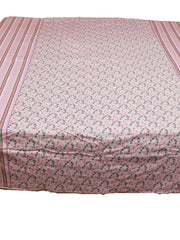 Dusty pink floral print dohar spread over a bed with striped pink and green borders