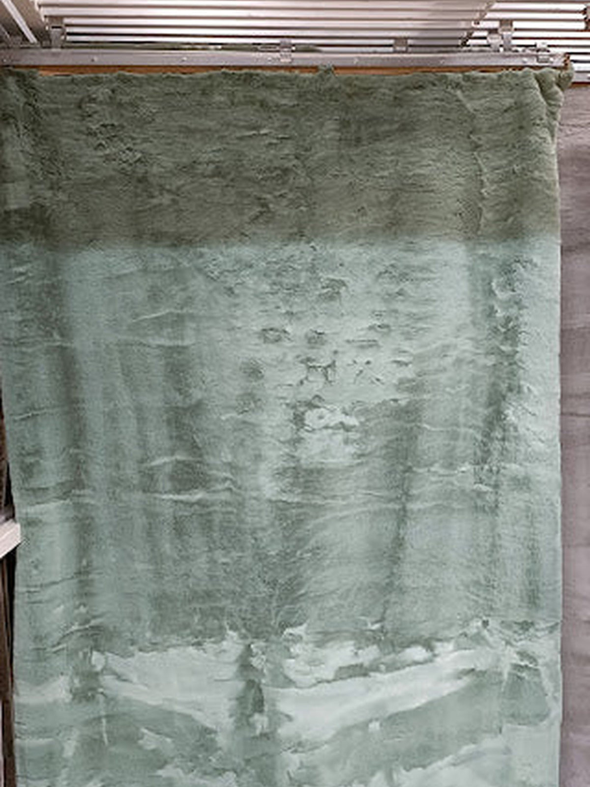Sage green artificial fur rug with a long, soft pile
