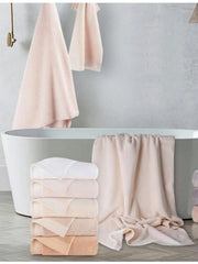 Blush cotton towels stacked and hanging beside a freestanding bath, hand towel range