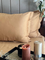 Honey sand sateen bedding set styled on a bed with pillows and a candle tray