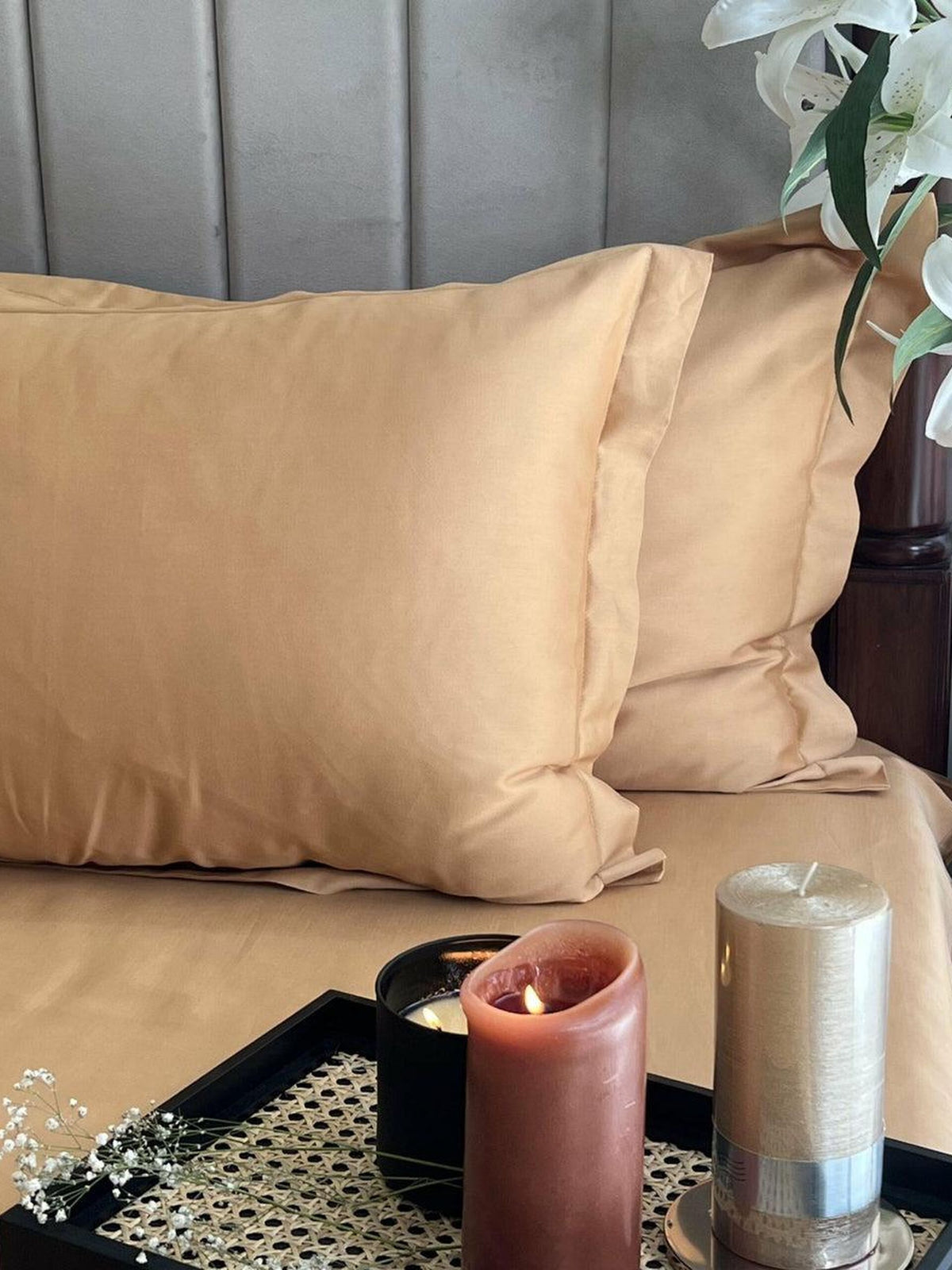 Honey sand sateen bedding set styled on a bed with pillows and a candle tray