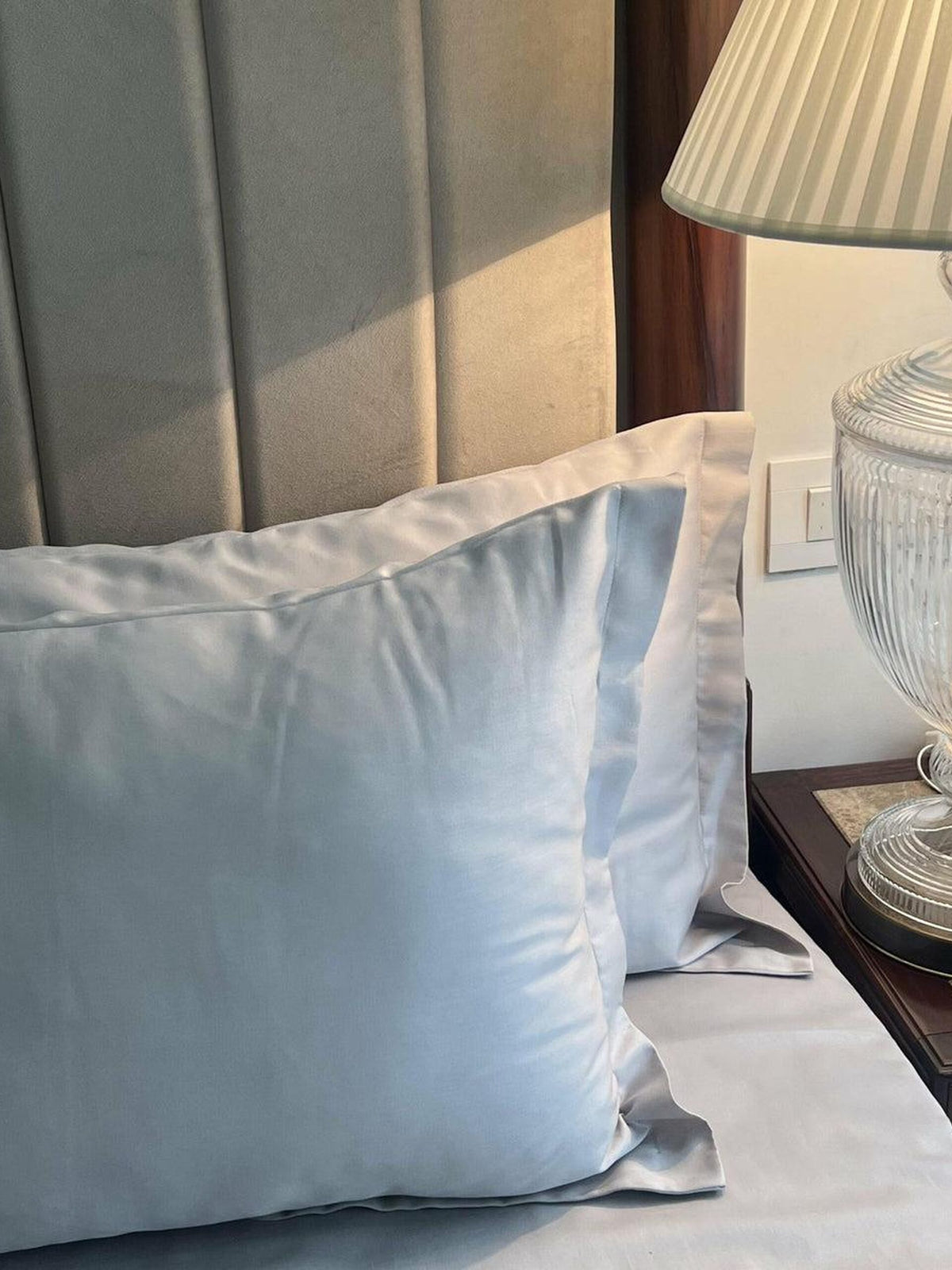 Pearl grey sateen pillows and bedding on a made bed