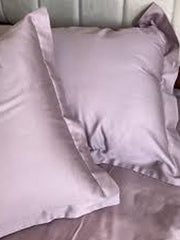 Mauve-grey satin pillow covers styled on a bed, close-up view