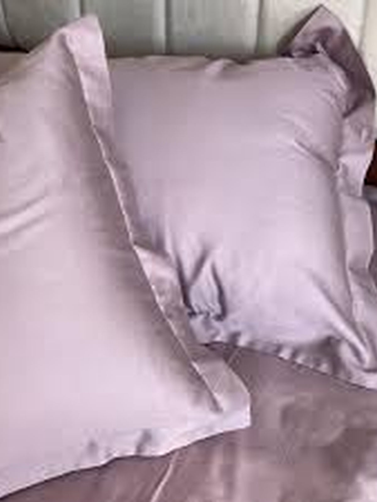 Mauve-grey satin pillow covers styled on a bed, close-up view
